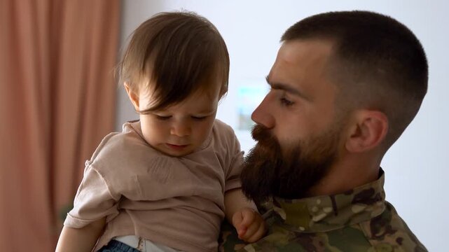 Male soldier in military uniform returning home to family - Father hugging baby son - Homecoming, happiness and love concept		
