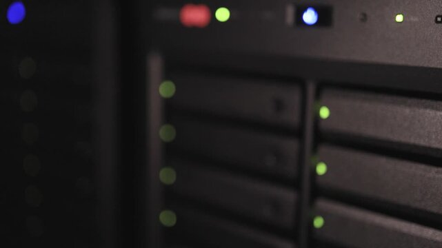 A wide view of server rack units with green LED indicator lights in a dark data center environment.