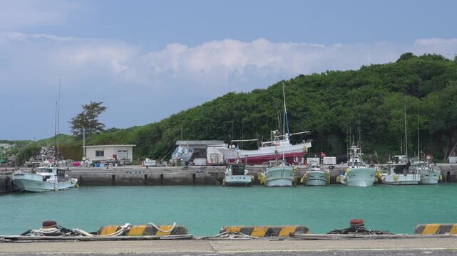 エメラルドグリーンの海に漁船が停泊するのどかな港の風景