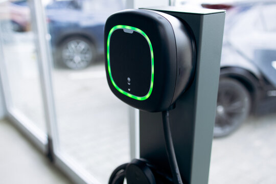 Electric vehicle charging station with a vibrant green light, signifying a fully charged battery, promoting sustainable transportation