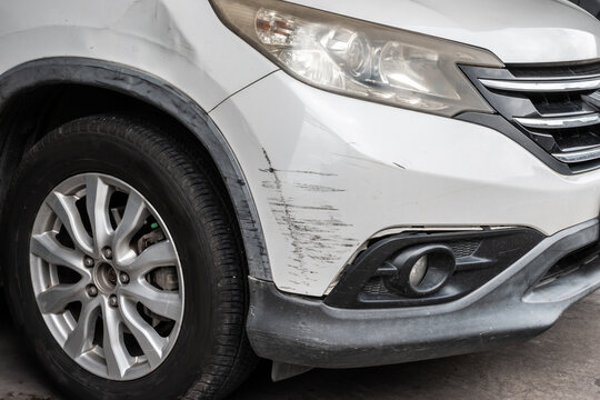 scratched and damaged front bumper on white car after accident