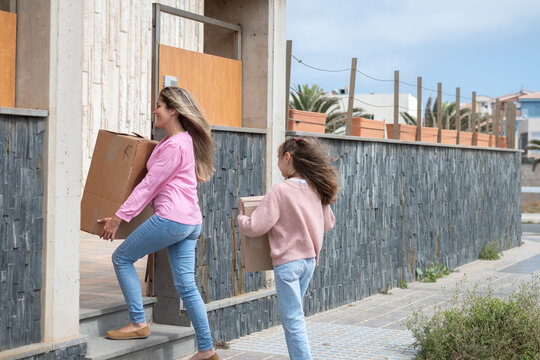 Mother and daughter carrying moving boxes into their new home