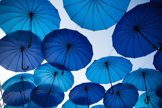 Blue and cyan umbrellas are arranged overhead in a bold geometric pattern, vibrant outdoor festival decoration, creative background.