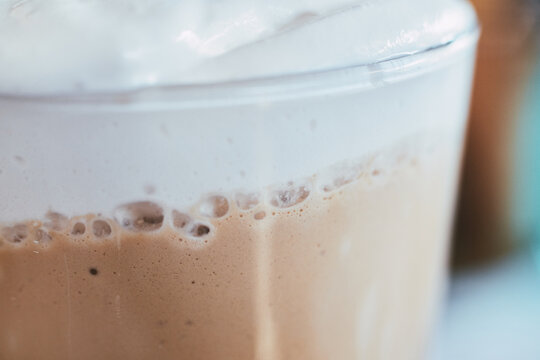 Close-up shot of a refreshing iced coffee beverage topped with thick creamy foam