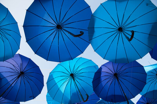 Blue umbrellas create a spacious graphic canopy against the sky, outdoor festival decoration, creative summer background.