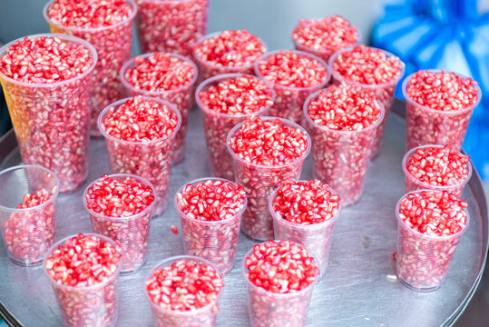 Fresh Pomegranate Seeds in Clear Plastic Cups Ready for Healthy Snacking at Market