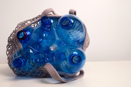 Blue empty plastic bottles in mesh string bag for recycling and waste management concept	