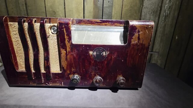 Antique radio receiver with distressed dark wood casing and golden speaker grill. Vintage technology from mid-20th century, displaying classic design and aged appearance. Historical communication