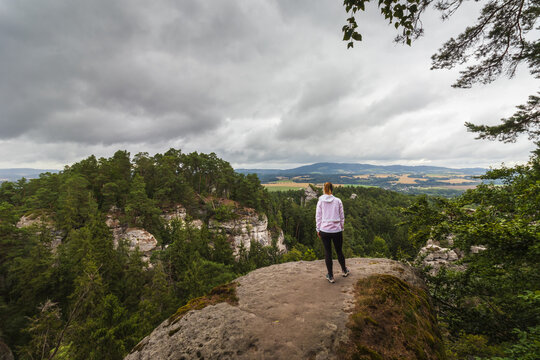 Woman hiker stands on a sandstone rock lookout in Hruboskalsko near Hruba Skala in Bohemian Paradise, Czech Republic