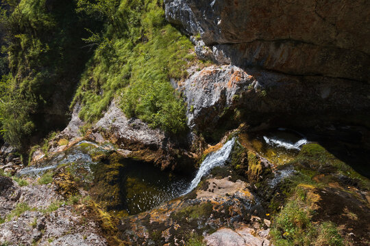 High angle view of water flowing through rocky cascades and mossy pools in a deep alpine canyon in Palfau, Austria