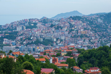 Fototapeta premium Elevated panoramic view of Zonguldak, a historic coal mining city on Turkey's Black Sea coast, featuring densely built hillside neighborhoods, lush greenery, and the coastal urban landscape.