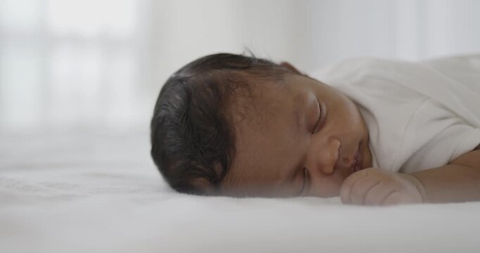 Closeup portrait of african happy baby sleeping sweet dream on bed over white background with copy space. Healthy newborn child take a nap asleep. Family love newborn healthcare medical concept.