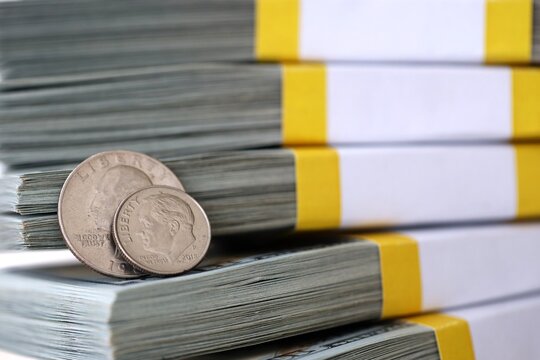 US coin lies among ten thousand dollars packs in stack on big amount of hundred dollar bills