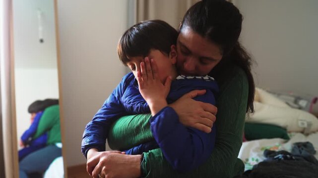 Mother comforts sad school age son with warm embrace at home, expressing emotional support, unconditional love, secure attachment and family reassurance