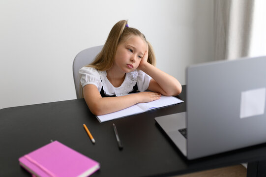 Exhausted Schoolgirl Leaning Head on Hand during Remote Online Lesson at Home