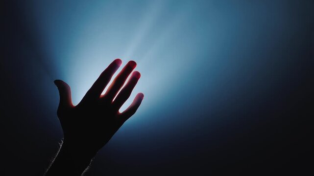 Two hands reaching out and joining in dramatic light, symbolizing hope and connection.