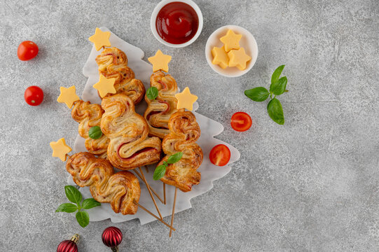 Puff pastry Christmas tree buns with cheese and ham on a marble board. Christmas and New Year appetizer. Top view, copy space.