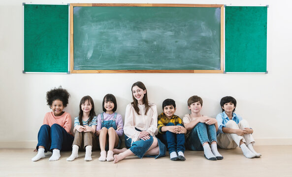 Portrait of teacher and group of multicultural students sit in classroom, asian caucasian children together in school. Home school education, diversity multicultural community. Back to school
