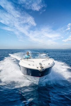Front view of a sports motorboat cruising with high speed over the blue sea