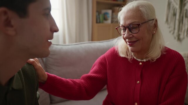 Senior Caucasian woman comforting young adult Caucasian man by holding hands and talking. Footage is ideal for senior care services, family support, and mental health awareness campaigns