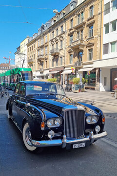 Basel, Switzerland, May 24, 2026: Vintage Luxury Car on European Street with Classic Architecture and Modern Tram