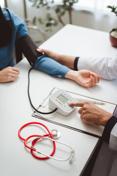 Doctor is seen using an automated blood pressure monitor on a patient's arm to perform a health check and encourage proactive monitoring of heart health