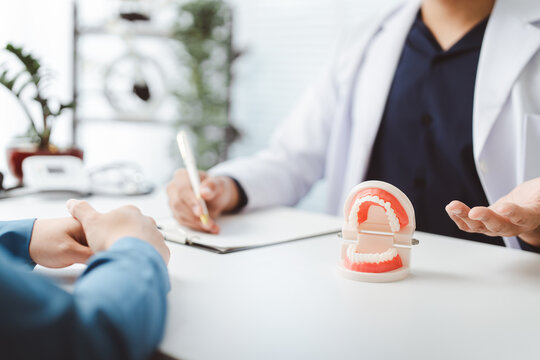 Dentist explaining complex dental procedure to patient in office using jaw model, discussing treatment options and oral health planning