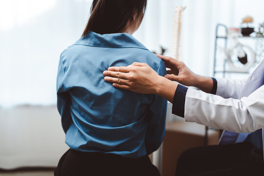 Doctor examining a patient's upper back, assessing for spinal issues and providing care for discomfort or injury, promoting health and wellness in a medical setting