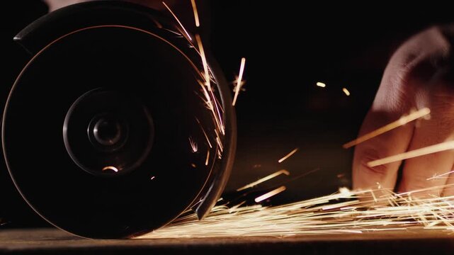 Industrial angle grinder cutting metal pipe with bright orange sparks flying in slow motion.