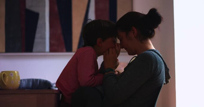 Mother and young son touch foreheads at home, expressing secure attachment, unconditional love and authentic family bonding