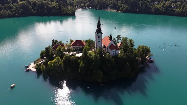 Aerial footage over Lake Bled Island Church on clear waters in Slovenia