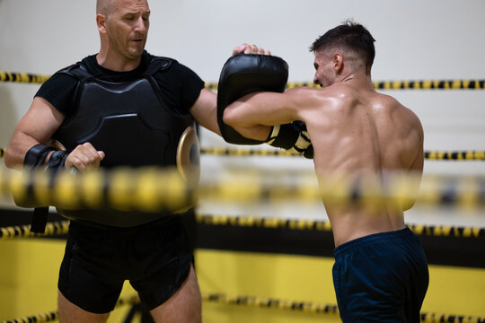 Boxer Training With Coach Doing Pad Work In Ring During Intense Boxing Workout Session
