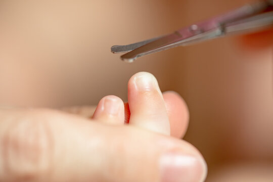 Close up view of scissors trimming fingernail on newborn baby finger