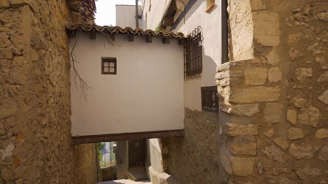 Traditional alley with a white overhanging passage between stone houses in old Cuenca Spain