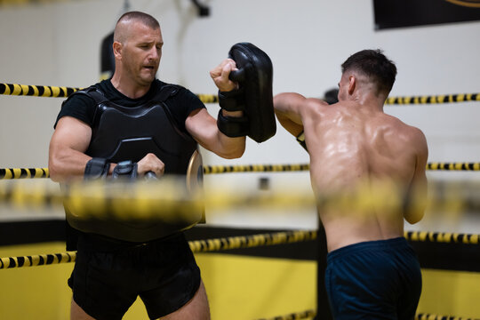 Boxer Training with Coach Holding Pads in a Boxing Ring During Intense Workout Session