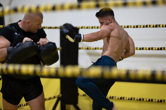 Male Boxer Training With Coach Pads During Intense Sparring Session In A Boxing Gym Ring