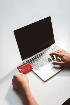 Person doing online shopping, using a credit card for payment, entering secure banking details on a laptop, performing e-commerce transactions and digital purchasing
