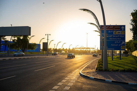 Doha Corniche Street with Road Signs and Cars at Sunset in Qatar