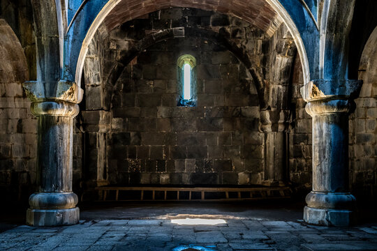 Stone Arches and Columns in Medieval Monastery Interior with Sunbeam on Floor