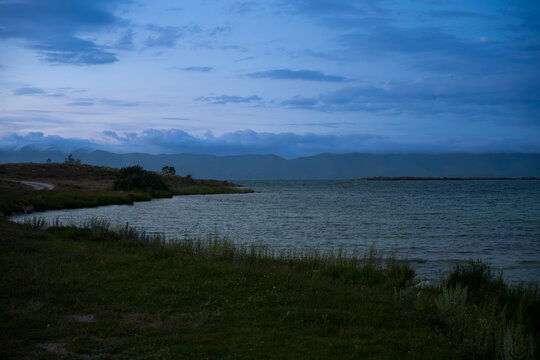 Tranquil Lakeside Cove in Blue Hour Twilight with Distant Clouds on Mountains