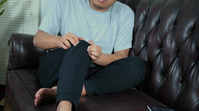A young man massages his knee due to knee pain and muscle aches caused by Runner's Knee or Patellofemoral Pain Syndrome, osteoarthritis, arthritis, rheumatism, and Patellar Tendinitis. Medical concept