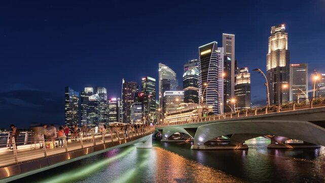 Asia, cityscape day to night transition zoom in time lapse of Singapore skyline and Marina Bay, showing a pedestrian footbridge leading to the financial district, with people walking and sightseeing