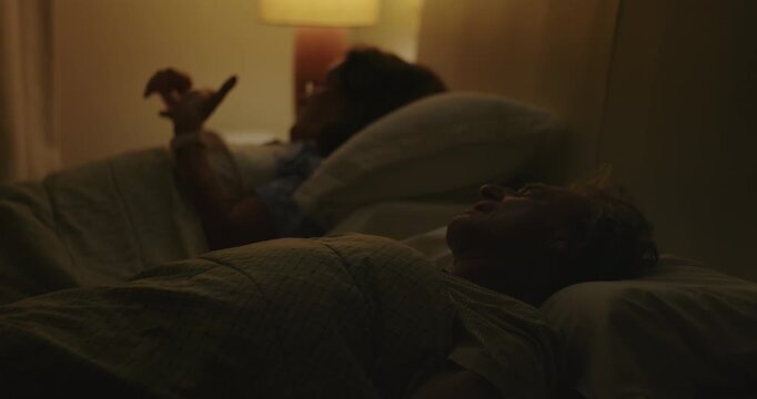 Senior woman putting smartphone away and switching off bedside lamp before sleep, completing a peaceful nighttime routine and embracing healthy bedtime habits at home