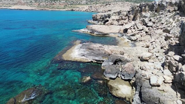 Aerial view of dramatic limestone cliffs and sea caves along the coastline of Cape Greco, Cyprus