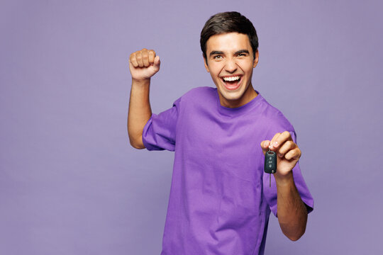 Young happy Caucasian man he wear violet t-shirt casual clothes hold car key fob keyless system do winner gesture isolated on plain pastel light purple background studio portrait. Lifestyle concept.