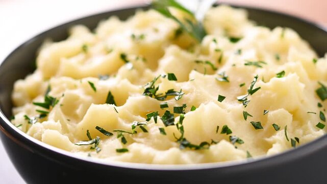 Creamy mashed potatoes rotating on wooden table