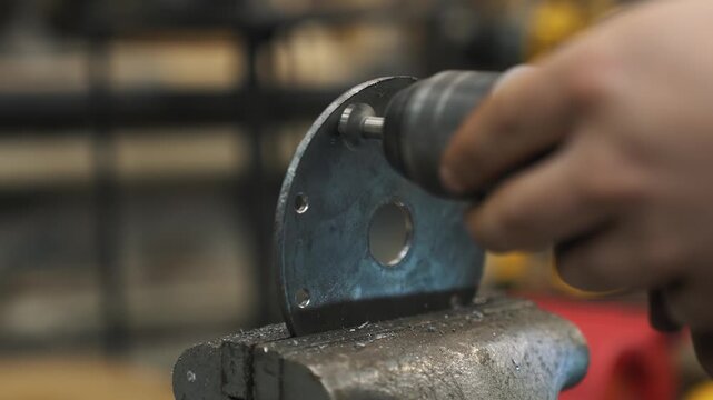 An engineer drills holes in a steel plate that will serve as the core for a gear train with a sprocket and chain.