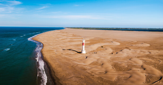 Fangar Lighthouse on remote sandy peninsula with Mediterranean coastline and dunes in the Ebro Delta aerial panorama