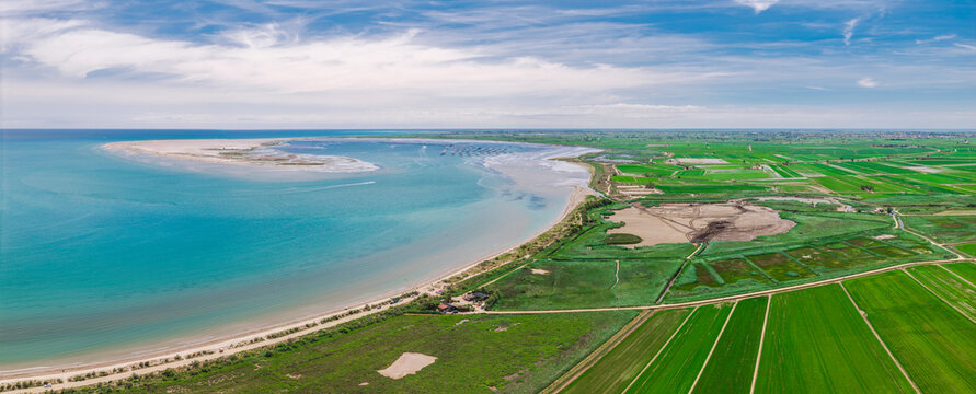 Ebro Delta coastline with turquoise lagoon, wetlands and rice fields viewed from above in Catalonia, Spain