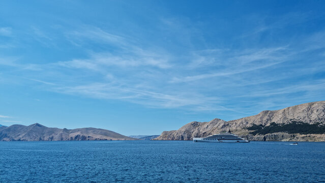 A luxury yacht anchored in the blue sea of Baska bay with Prvic island on the left and Krk island on the right side.